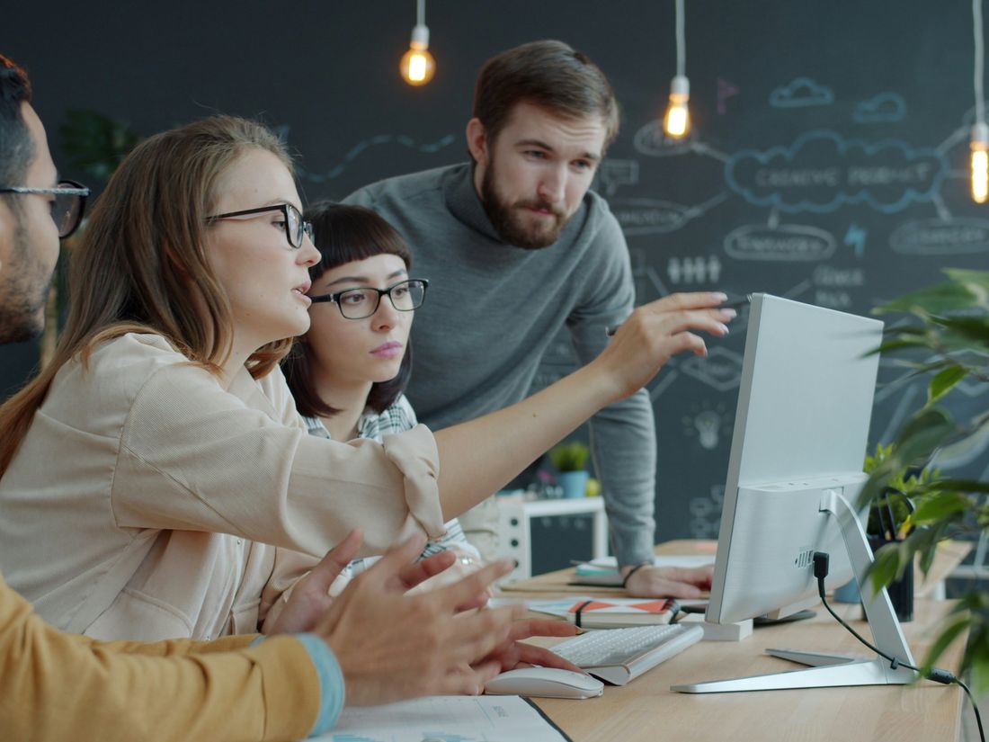 Consultants collaborating around a screen in an office